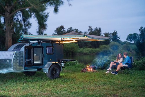 Couple sitting next to campfire and Brumby 121 Tear Drop Camper