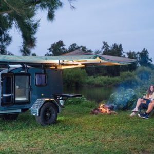 Couple sitting next to campfire and Brumby 121 Tear Drop Camper